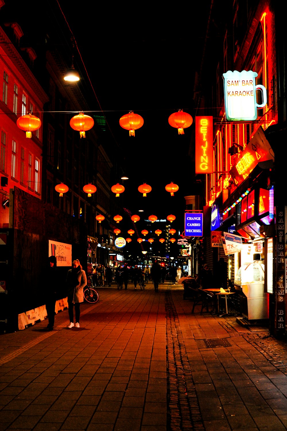 a person standing on a sidewalk in a city at night