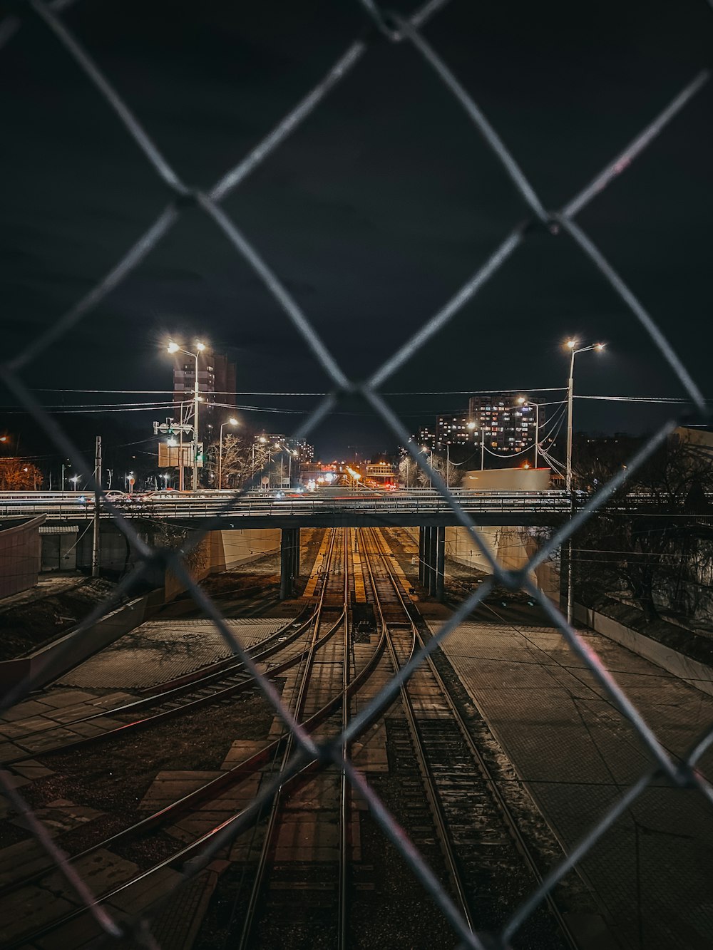 gray metal fence near city buildings during night time