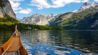 brown boat on lake near green mountain under blue sky during daytime