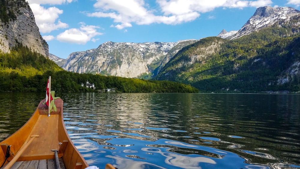 brown boat on lake near green mountain under blue sky during daytime