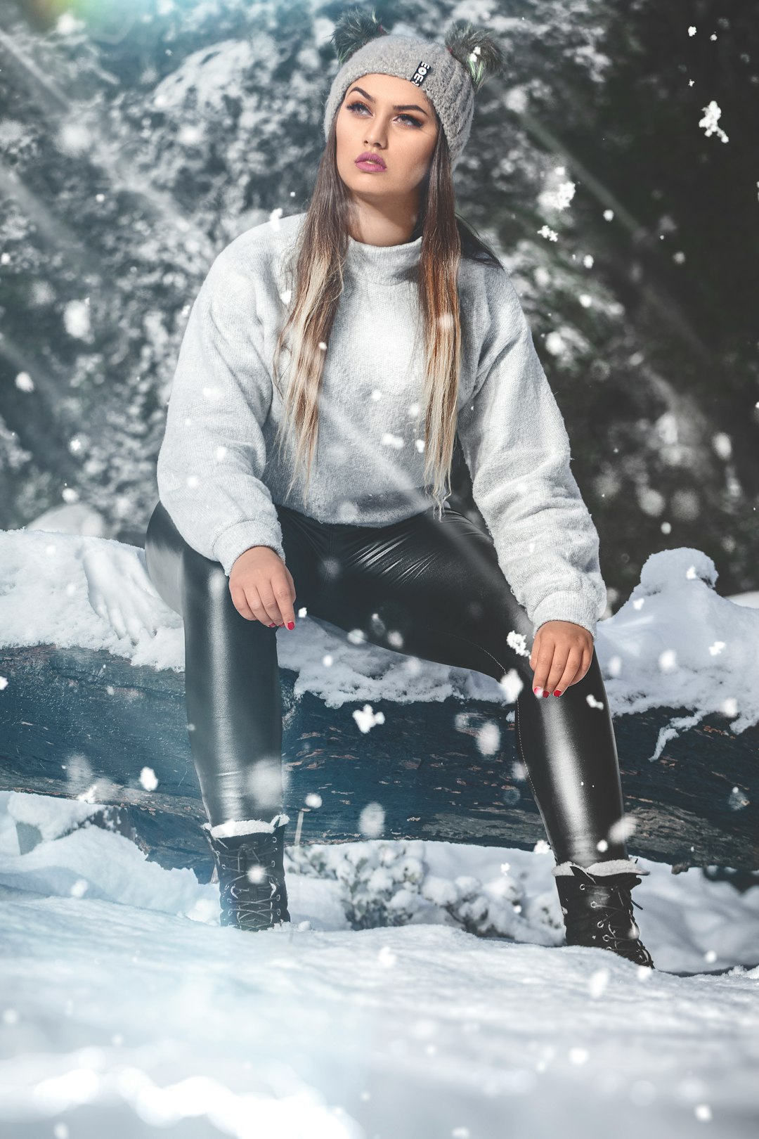 woman in white jacket and black pants sitting on snow covered ground during daytime