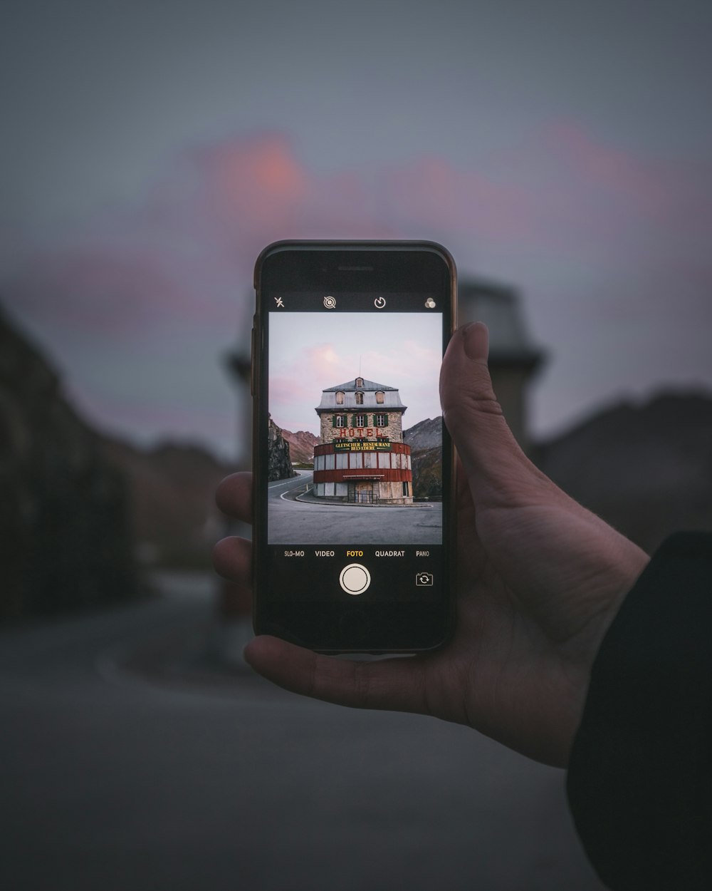 person taking photo of city during sunset