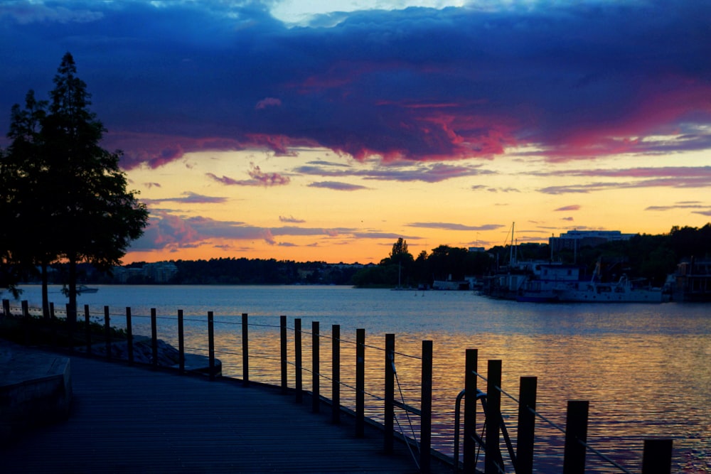 brown wooden dock on body of water during sunset