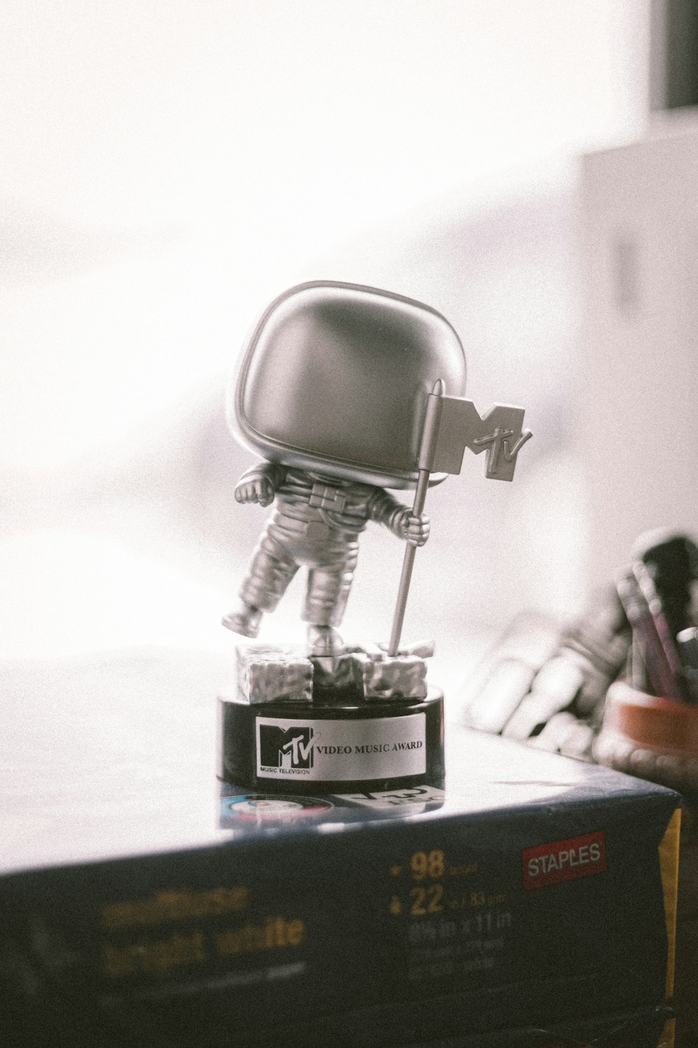 a small robot figurine sitting on top of a stack of books