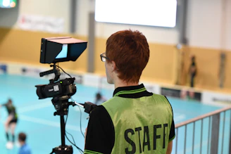 man in green and black nike crew neck shirt standing in front of black camera