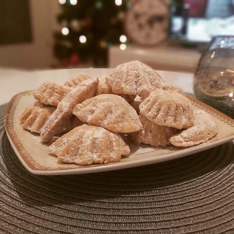 A tray of putri salju cookies covered in a snowy layer of powdered sugar, inviting and fresh.