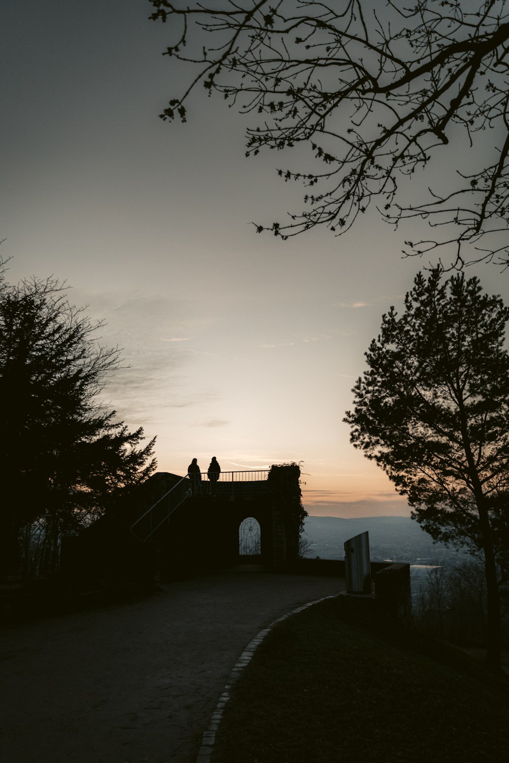 silhouette of house near body of water during sunset