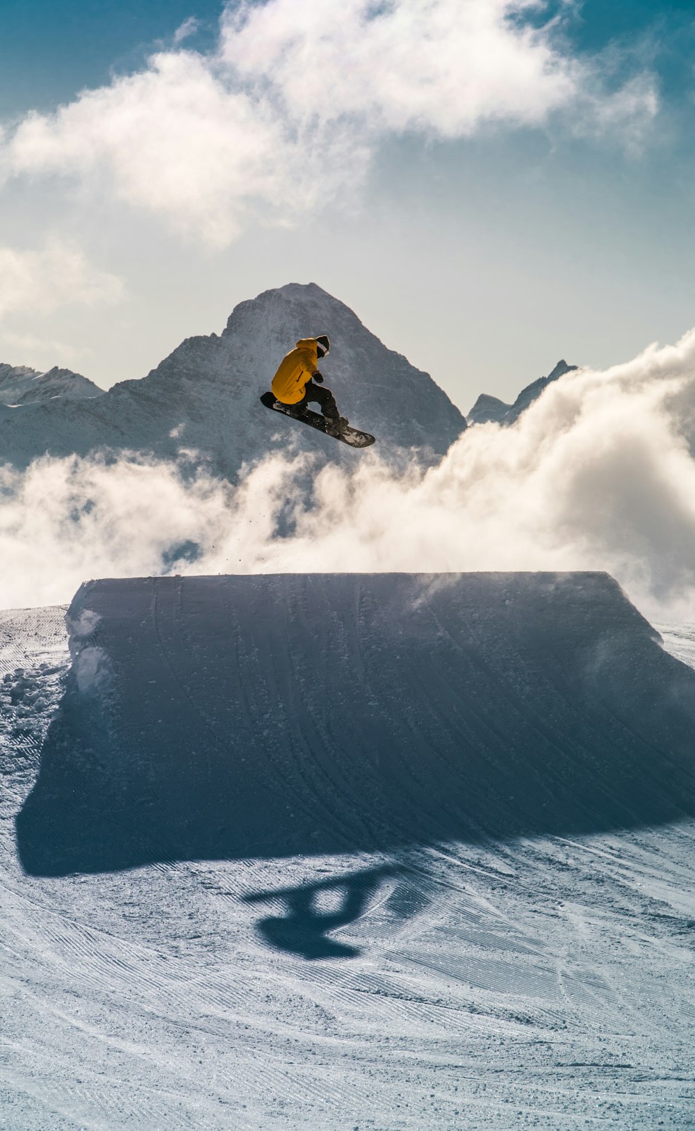 man in orange jacket and black pants riding on snowboard on snow covered mountain during daytime