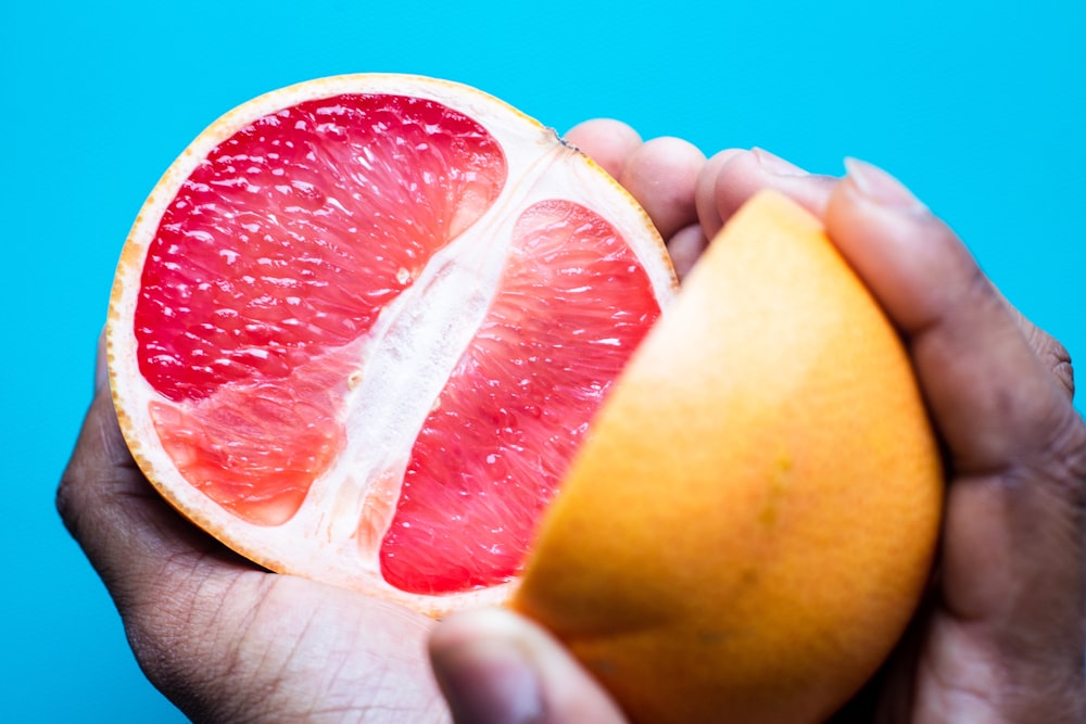 a person holding a grapefruit in their hand