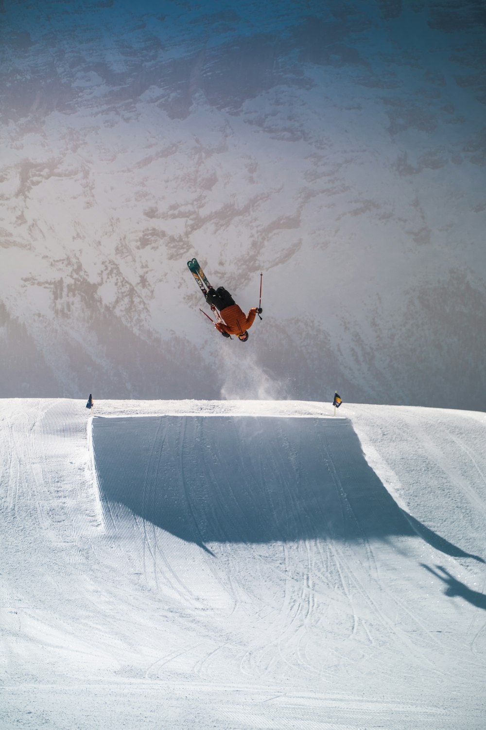 person in orange jacket riding on orange and white snowboard during daytime