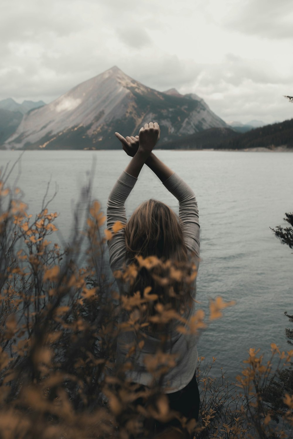 woman in black long sleeve shirt sitting on brown grass near lake during daytime