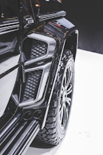 Close-up view of a modified vehicle with rugged, large tires and an intricate design. The image highlights the detail in the texture and contours of the vehicle's exterior, showcasing a luxury, customized appearance.