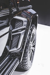 Close-up view of a modified vehicle with rugged, large tires and an intricate design. The image highlights the detail in the texture and contours of the vehicle's exterior, showcasing a luxury, customized appearance.