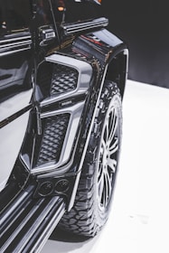Close-up view of a modified vehicle with rugged, large tires and an intricate design. The image highlights the detail in the texture and contours of the vehicle's exterior, showcasing a luxury, customized appearance.