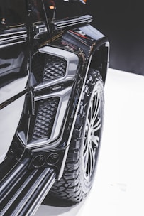 Close-up view of a modified vehicle with rugged, large tires and an intricate design. The image highlights the detail in the texture and contours of the vehicle's exterior, showcasing a luxury, customized appearance.