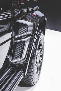 Close-up view of a modified vehicle with rugged, large tires and an intricate design. The image highlights the detail in the texture and contours of the vehicle's exterior, showcasing a luxury, customized appearance.