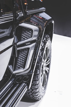 Close-up view of a modified vehicle with rugged, large tires and an intricate design. The image highlights the detail in the texture and contours of the vehicle's exterior, showcasing a luxury, customized appearance.