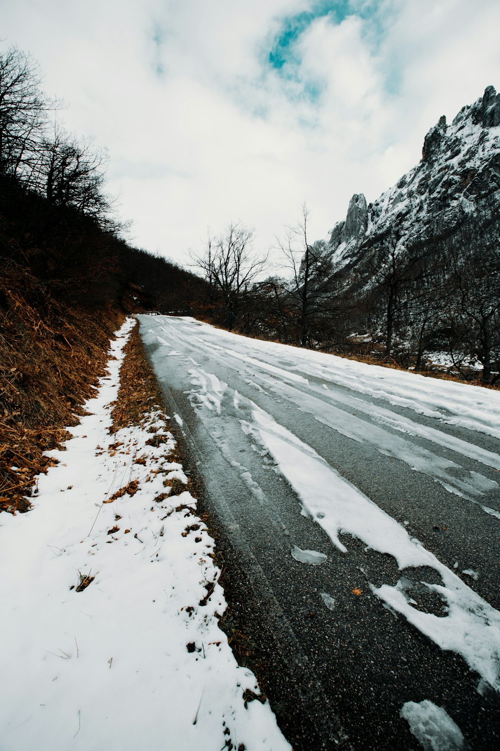 gray asphalt road between snow covered ground