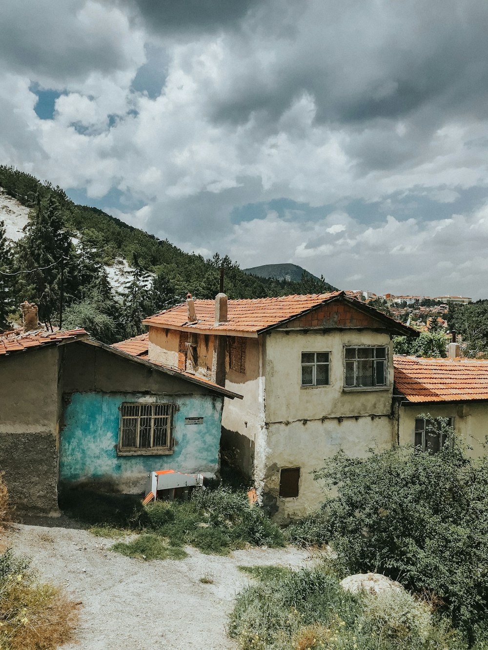 Maison en béton blanc et brun près des arbres verts sous les nuages blancs pendant la journée