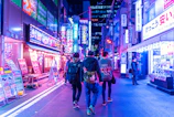 A lively street scene at night with neon signs and people enjoying the sonidero vibe.