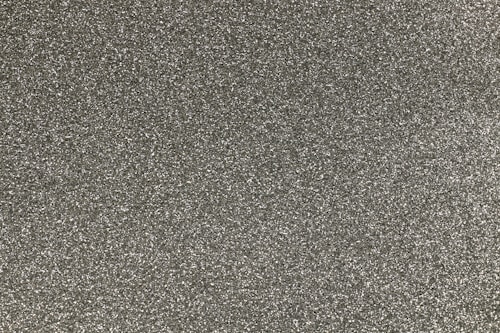 A close-up view of a textured gray surface covered in tiny particles, resembling sandpaper or a rough mineral texture.