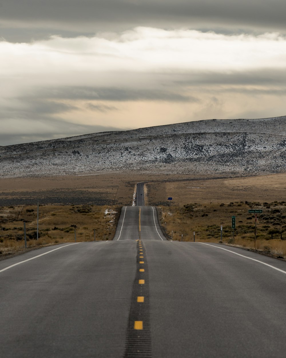 gray asphalt road in the middle of brown field during daytime