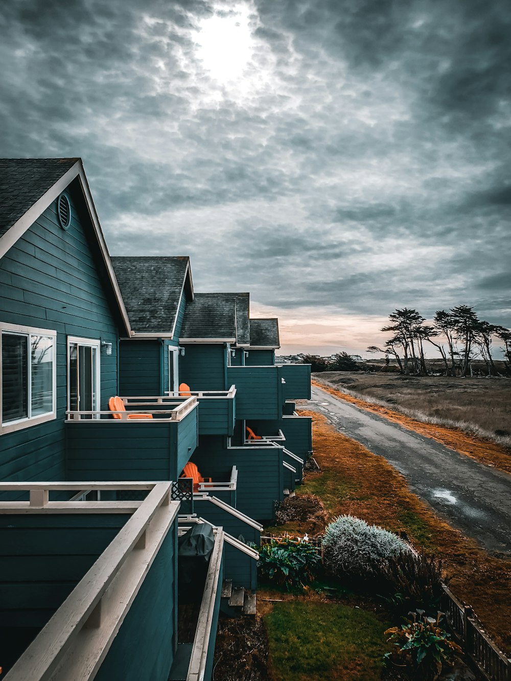 white and black wooden house near green grass field under gray clouds