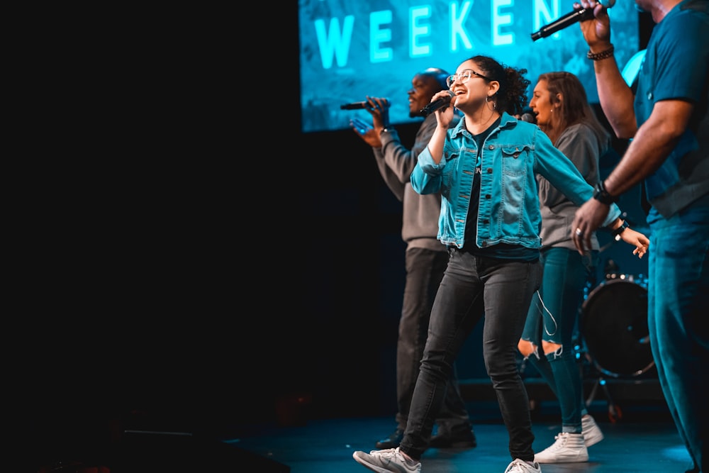 woman in blue denim jacket and blue denim jeans standing on stage