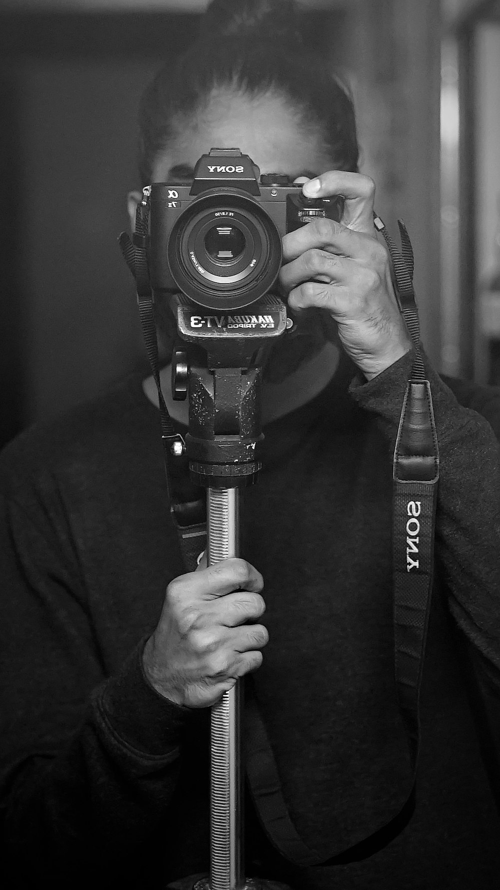 grayscale photo of man holding nikon dslr camera