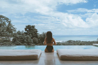 woman in black bikini sitting on brown wooden dock during daytime