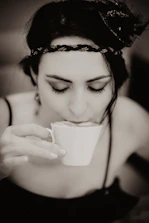 Woman peacefully drinking Beauty Sleep powder before bedtime in a cozy lit room.