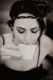 Woman peacefully drinking Beauty Sleep powder before bedtime in a cozy lit room.