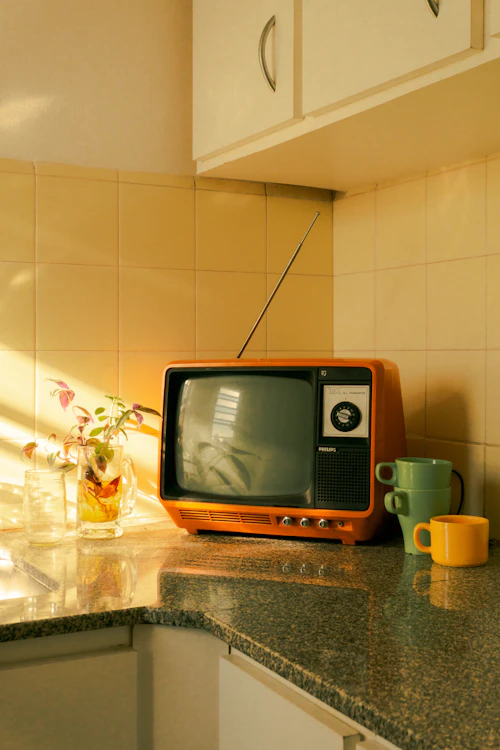 An orange vintage television on a kitchen counter
