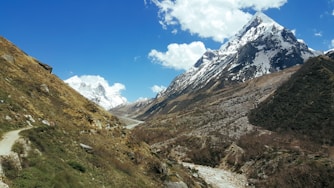 Panoramic shot of snow-capped peaks and a clear blue sky over a trekking path.
