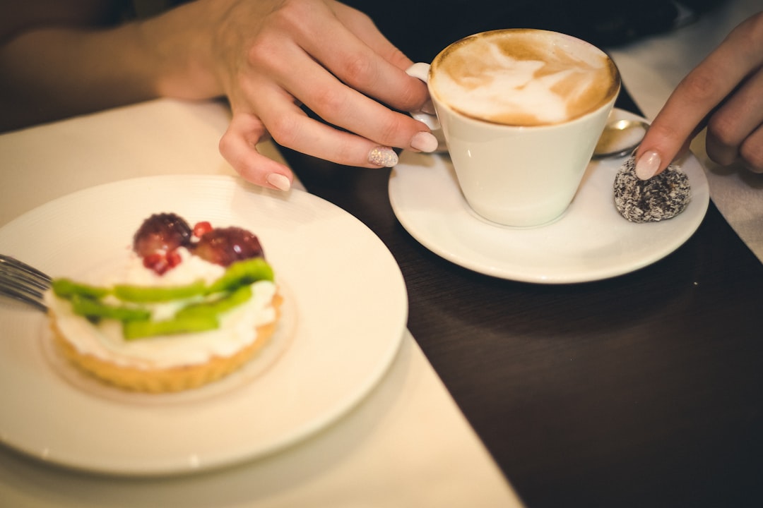 person holding white ceramic mug with brown liquid