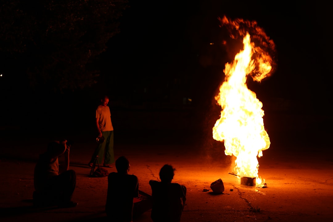 man in white t-shirt standing near bonfire during nighttime