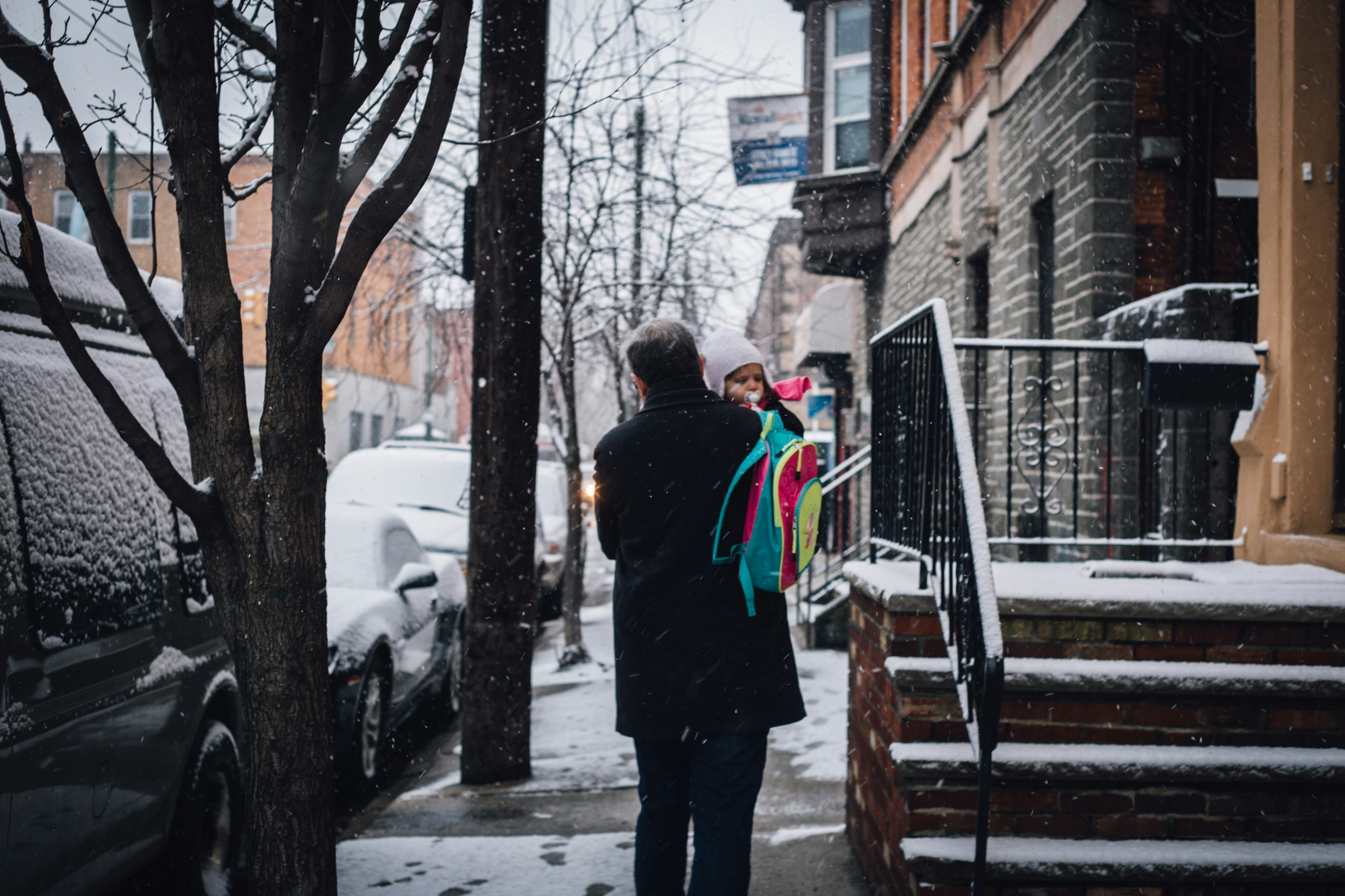 Hombre en chaqueta negra de pie en escaleras cubiertas de nieve