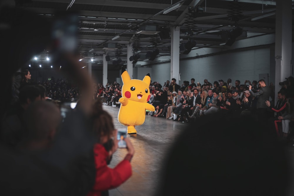 Personas en un concierto con la mascota amarilla de Pokémon Pikachu