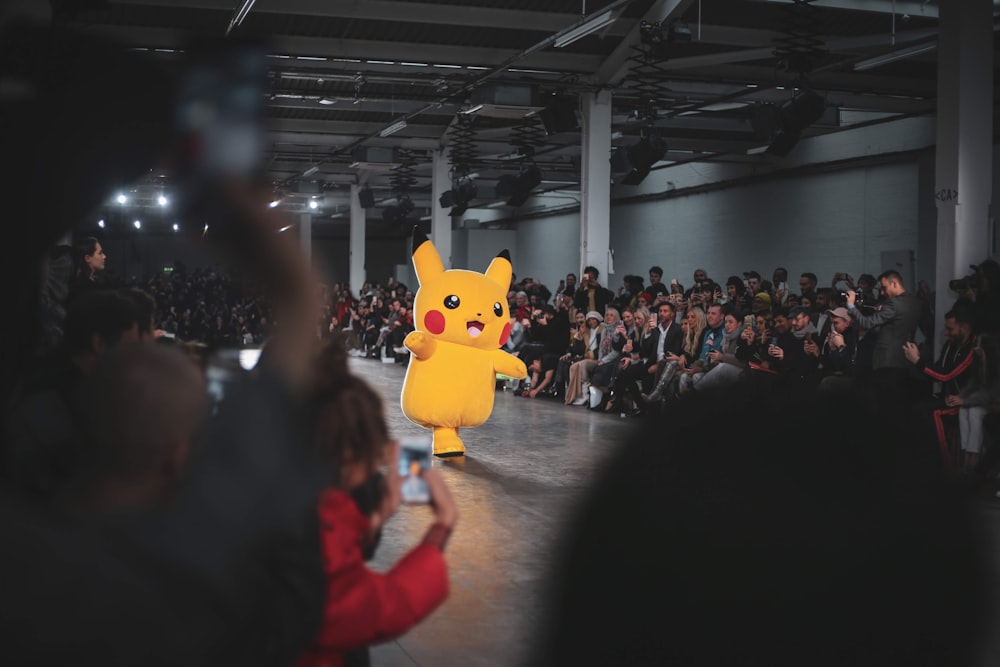 pessoas em um concerto com o mascote amarelo pokemon pikachu