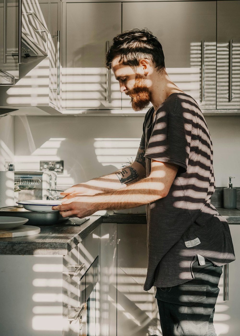 man in black and white stripe shirt and black pants standing in kitchen