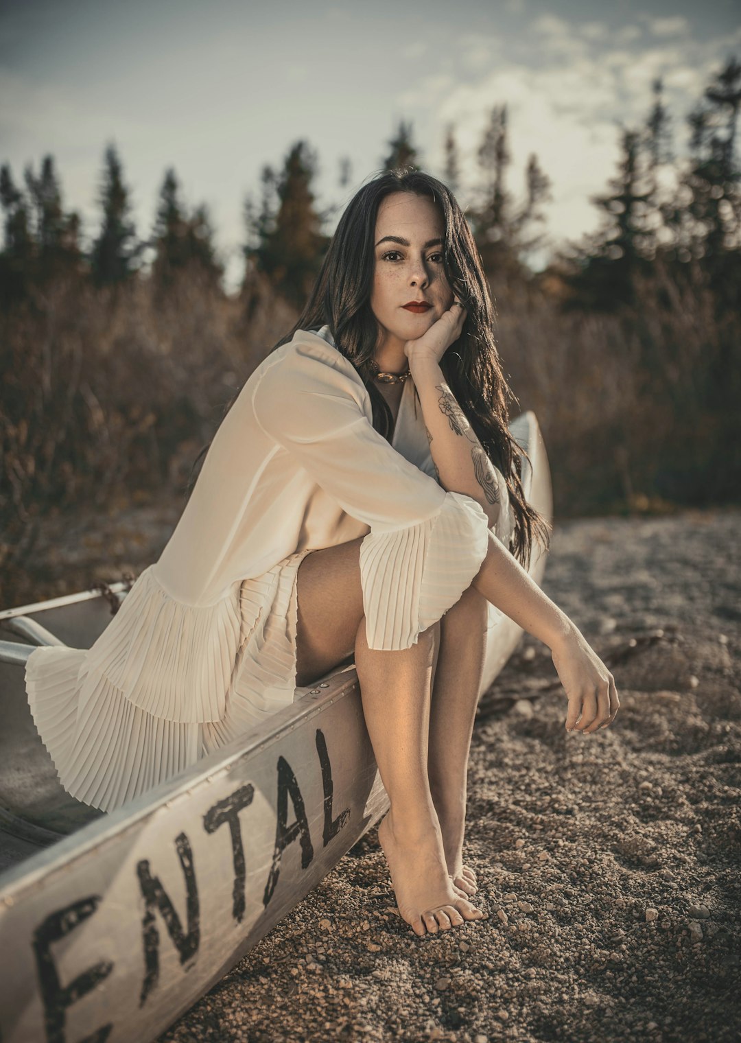 woman in beige dress sitting on white and black surfboard