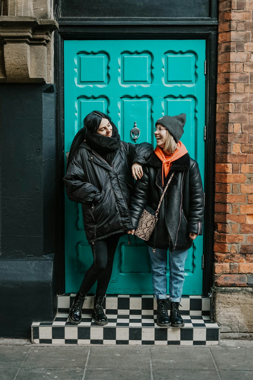 woman in black leather jacket standing beside red door