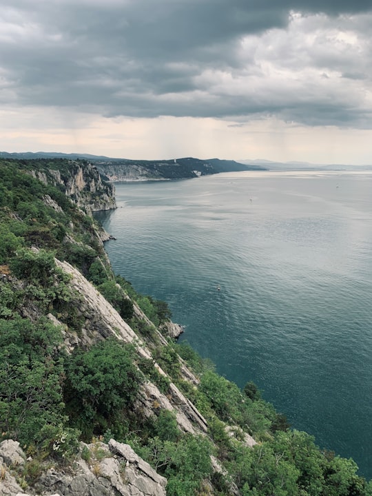 green and brown mountain beside body of water under cloudy sky during daytime in Sentiero Rilke Italy