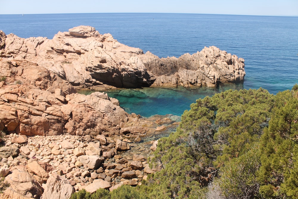 brown rocky mountain beside blue sea under blue sky during daytime