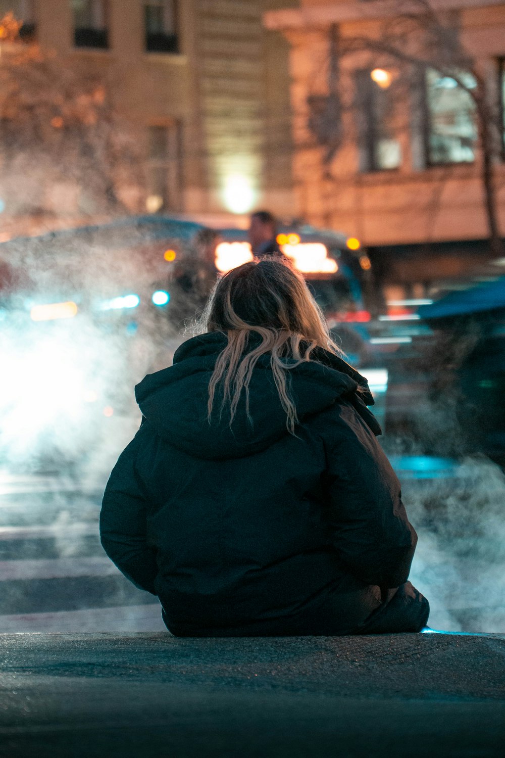 Frau in schwarzem Kapuzenpullover tagsüber auf dem Bürgersteig