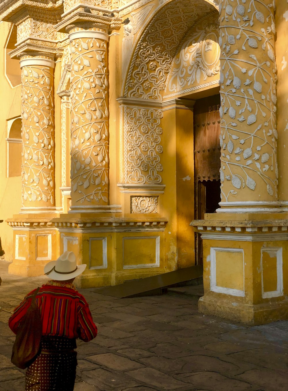 woman in red dress standing near brown and white floral pillar