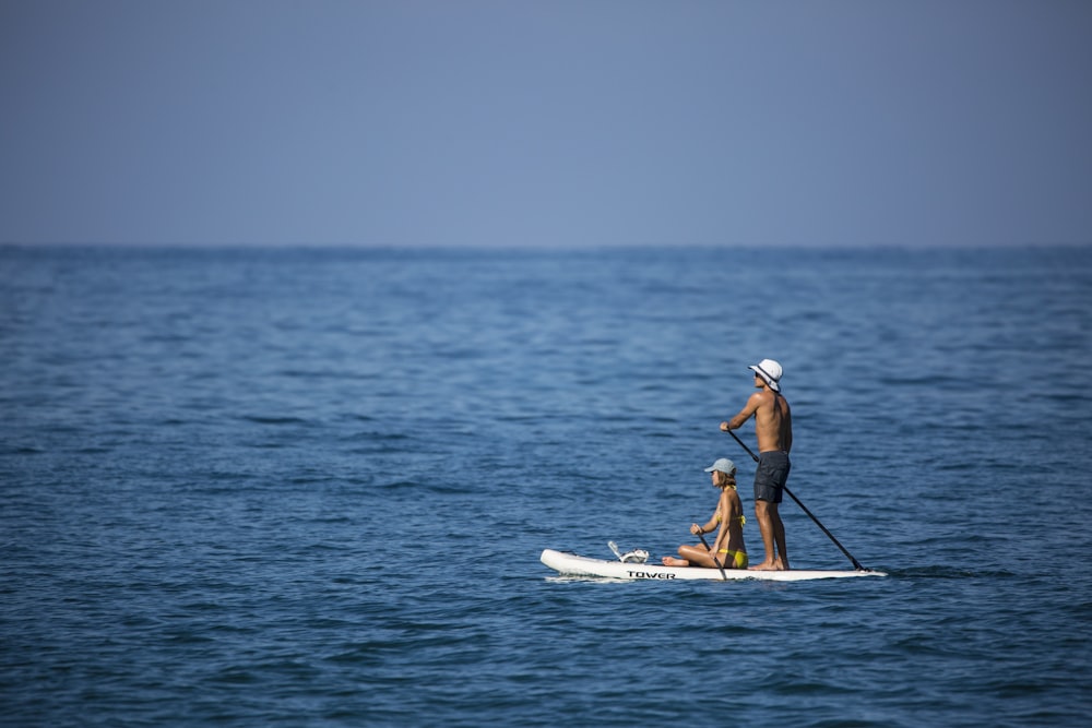 2 hombres con camisa blanca y azul montando kayak blanco y amarillo en el mar azul durante