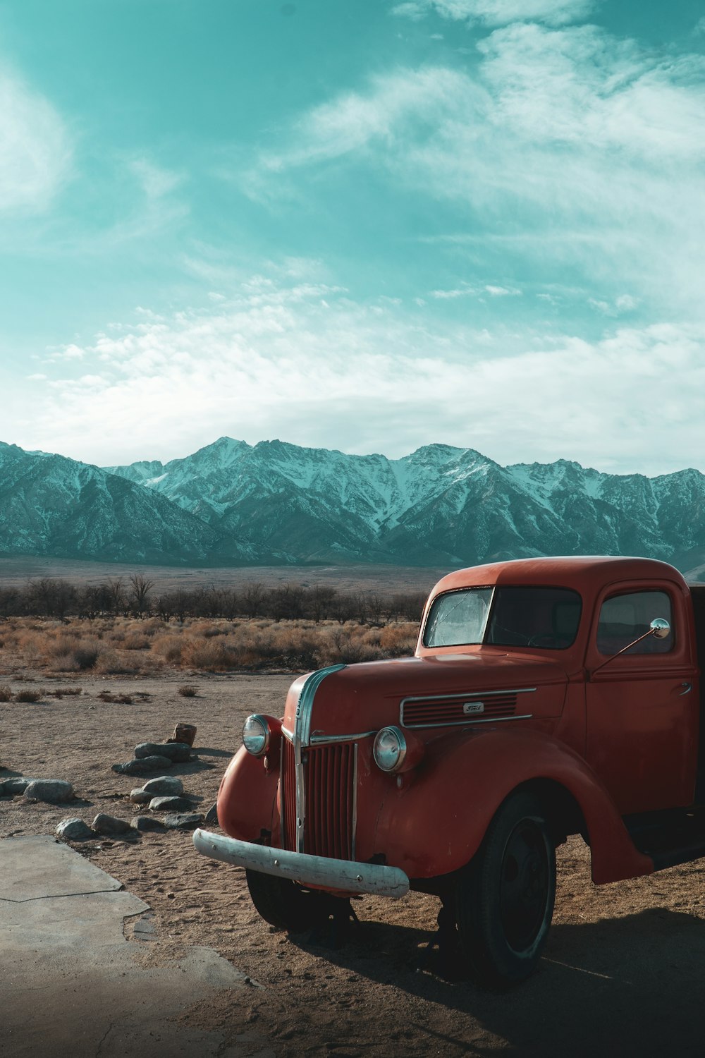 red car on brown soil near green mountains during daytime