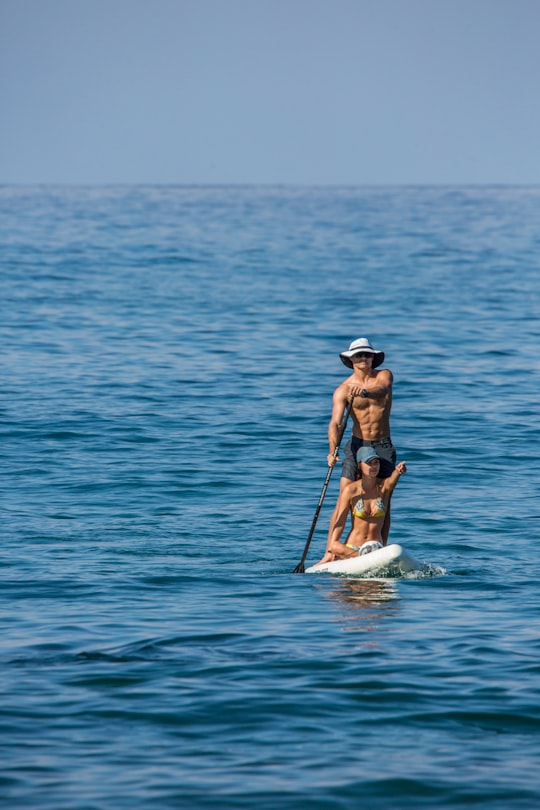 woman in blue bikini on white surfboard in the middle of sea during daytime in Sayulita Mexico