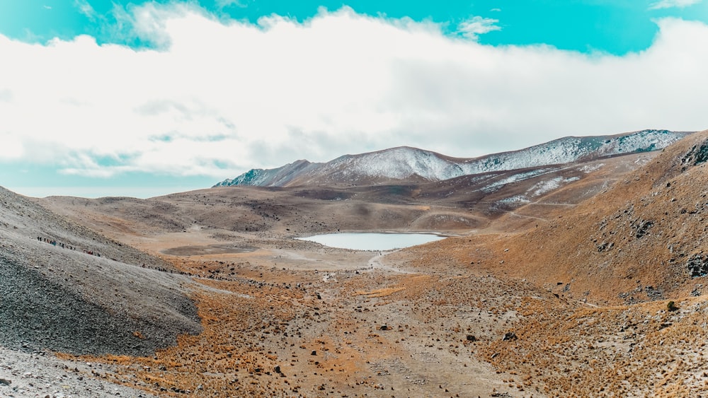 Montagnes brunes et grises sous les nuages blancs et le ciel bleu pendant la journée